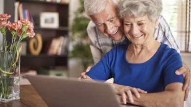 Smiling senior couple using laptop to look at types of senior living options