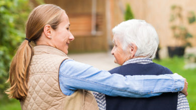 Young woman hugging senior family member living in memory care community