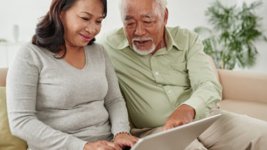 Senior man and his adult child using computer to find senior living communities
