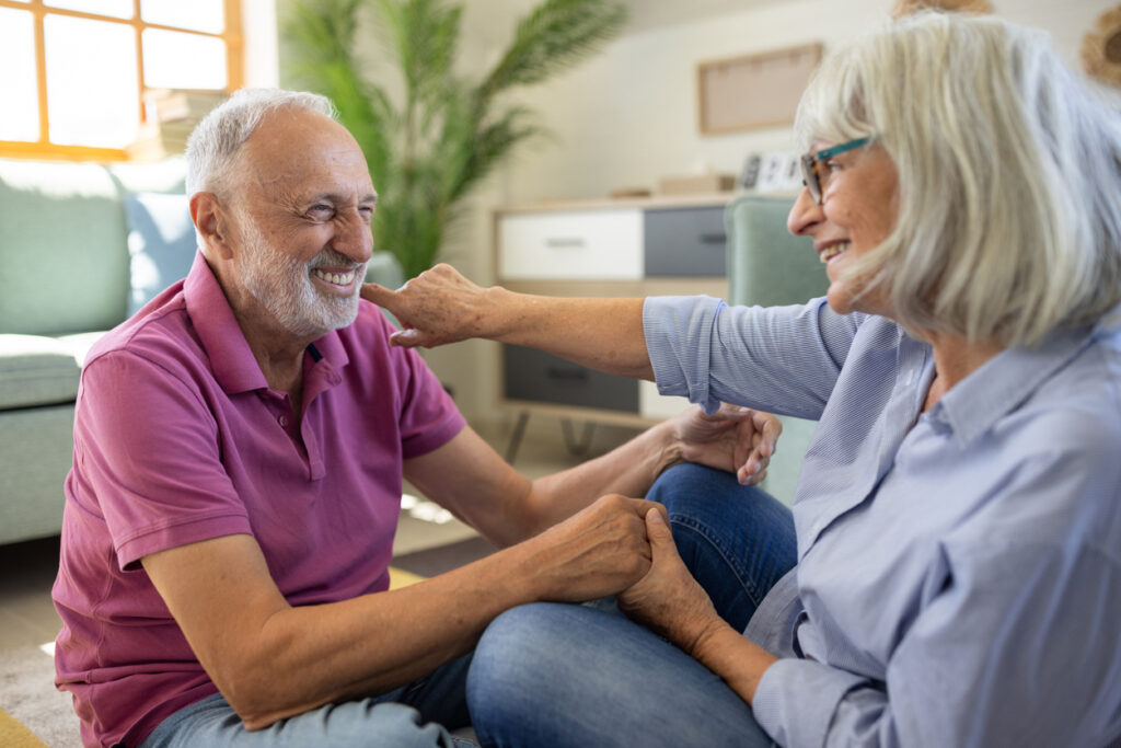 Senior couple sitting together, holding hands and smiling