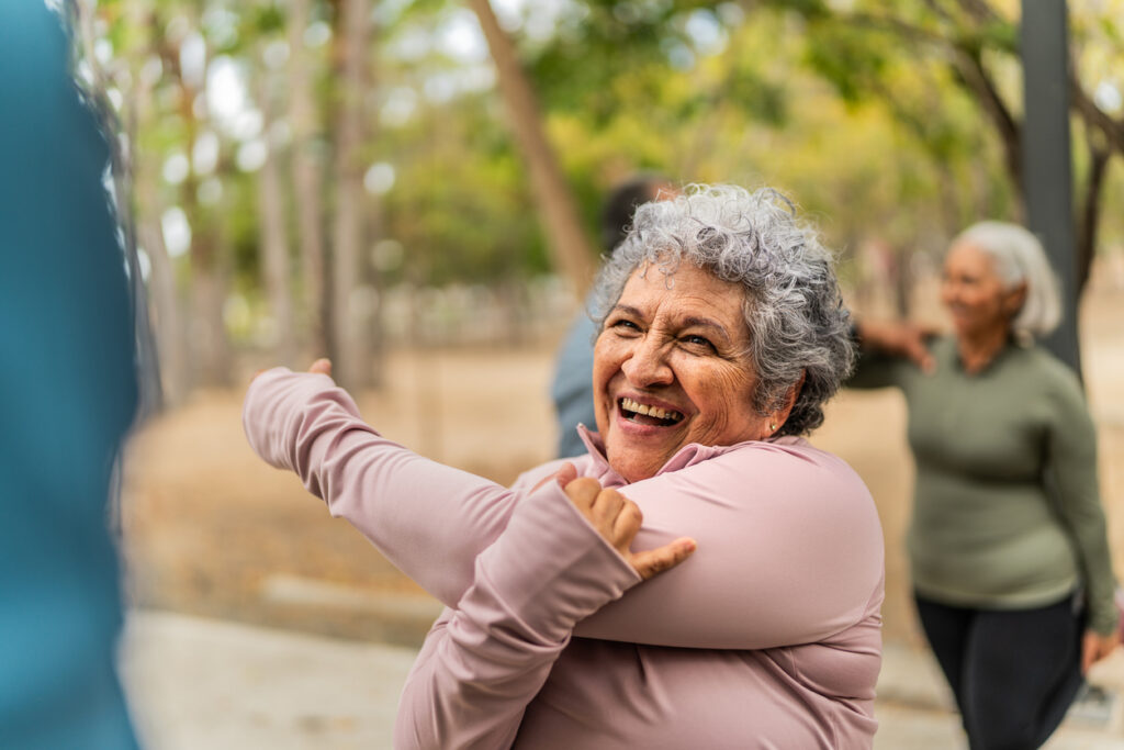 Senior woman stretching and talking to a friend at a public park